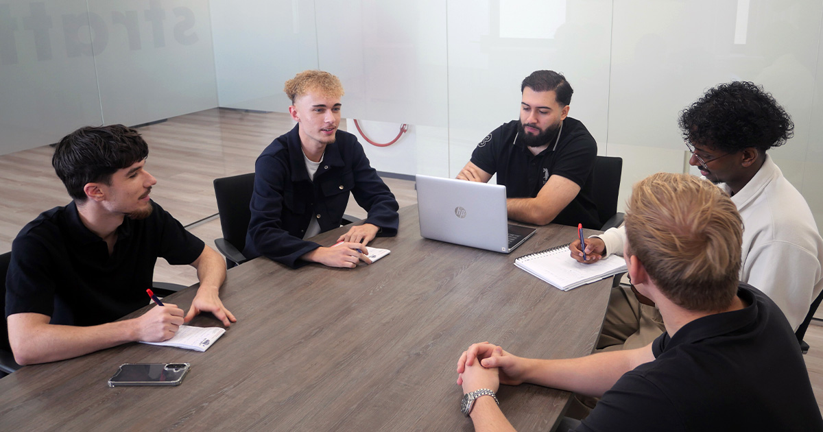Stagiairs van Stratt+ werken samen in een vergaderruimte aan een technisch-commercieel project.